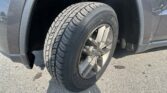 Front wheel and tire of a dark SUV, showing the alloy rim and tread pattern in the wheel well.