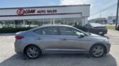 Front view of a silver sedan parked in a car dealership lot with an E-Z Loan Auto Sales sign on the building.