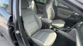 Interior of a car with light gray fabric seats, showing the front passenger and driver areas, center console, and door panels in daylight.