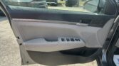 Interior of a car door with window/lock controls, view of a parking lot of SUVs through an open window