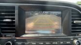 Car dashboard screen showing rearview camera with parking guideline lines and the message 'Check surroundings for your safety'.
