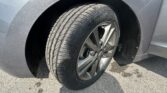 Close-up of a car wheel and tire in the front fender area, showing a silver alloy rim and wheel well.