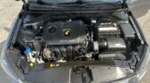 Open car hood showing the engine bay with a black DOHC 16V engine cover, battery on the right, and windshield wipers visible behind the hood edge.” ,