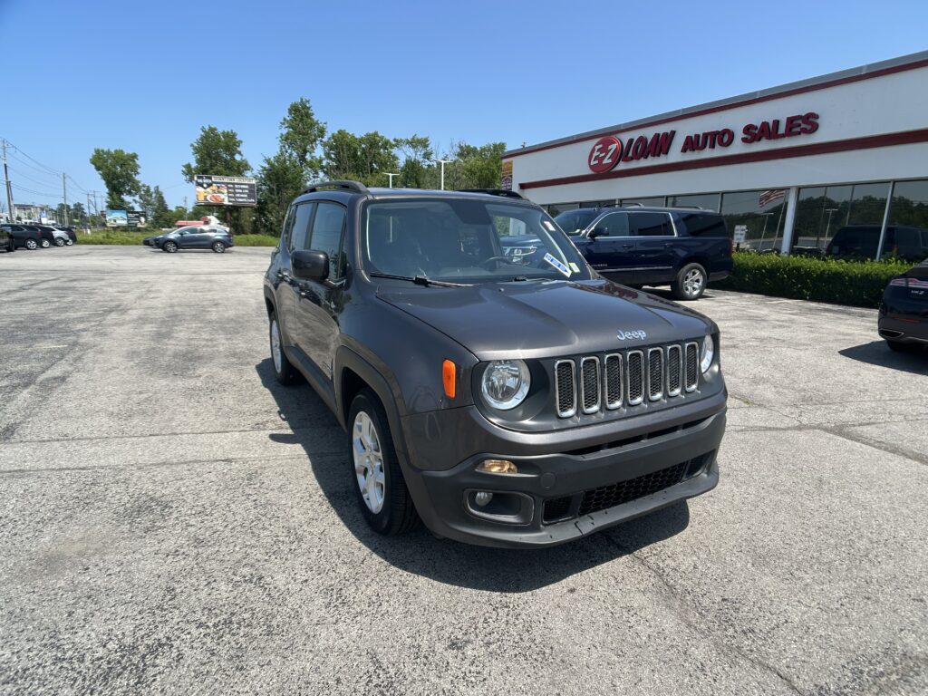 Gray Jeep SUV in a dealership parking lot with EZ LOAN AUTO SALES sign on the building in the background.