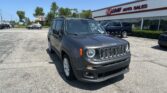 Gray Jeep SUV in a dealership parking lot with EZ LOAN AUTO SALES sign on the building in the background.