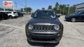 Front view of a gray Jeep in a car dealership parking lot with a red E-Z Loan sign in the background.