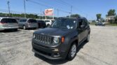 Front corner of a dark gray Jeep in a car lot with an EZ LOAN Auto Sales sign nearby on a sunny day.