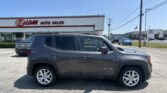 Dark gray Jeep Renegade SUV in a parking lot in front of EZ Loan Auto Sales storefront on a sunny day