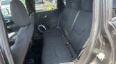 Interior of a dark fabric SUV back seat with two visible headrests and three seating positions, seat belts fastened, side door panel, and window view of parked cars outside