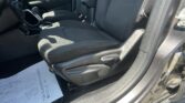 Front interior of a car: driver seat and center console with a paper document on the floor by the door, black fabric seats and seatbelt visible.