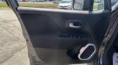 Interior of a car door with window controls, outside a dealership parking lot visible through the window side mirror.