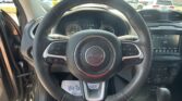 Jeep steering wheel front and center with dashboard and touchscreen visible in the background.