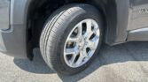 Close-up of a car wheel and tire on a gray SUV, showing the alloy rim and tread pattern near the front wheel well.