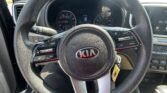 Steering wheel close-up in a Kia car, with the dashboard and control buttons visible around it.
