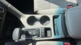 Interior of a car center console with two cup holders and gear shifter visible, seat belt buckle on the right.