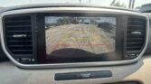 Car dashboard with rear-view camera screen showing parking guidelines and the message 'Check surroundings for your safety.'
