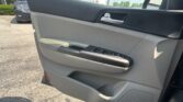 Close-up of a car door interior: armrest, silver door handle, power window controls, and speaker grille; parking lot visible outside.]','