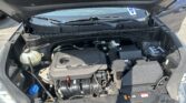Under-hood view of a car engine bay with the coolant reservoir on the left and wiring and battery visible on the right.