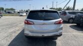Rear view of a white Chevrolet Equinox in a crowded parking lot on a sunny day
