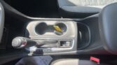 Car interior center console with two cup holders, gear shifter, and a yellow tag on the key resting in the holder.