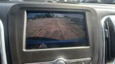 Rearview camera display in a car showing parking lot behind with orange guide lines on the screen