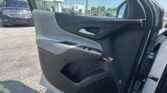 Inside of a car door showing the armrest, door handle, and window controls, with a dealership lot visible through the window behind.