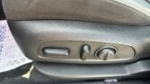 Close-up of a car seat side panel showing two adjustment levers and a round control knob for seating position adjustments.