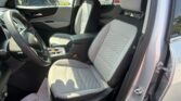 Interior of a Chevrolet SUV showing two front seats with gray quilted upholstery and parked cars outside through the windshield.