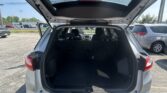 Open rear hatch of a silver SUV showing roomy cargo area and folded third-row seats in a parking lot.