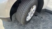 Close-up of a car's front wheel and tire in the wheel well, showing the tread and alloy rim on a beige SUV.