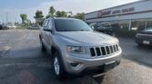 Silver Jeep SUV in the foreground outside EZ Loan Auto Sales, with a row of parked cars and a blue sky above.