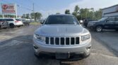 Front view of a silver Jeep SUV in a dealership lot, with an EZ LOAN Auto Sales sign on the left and other cars in the background.