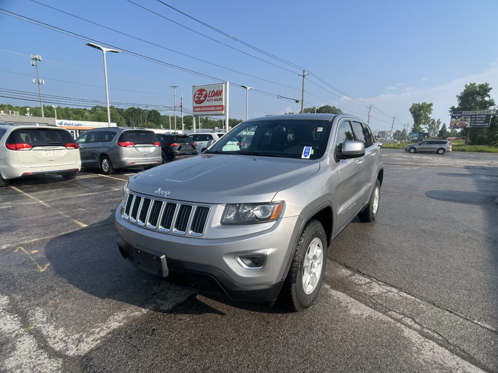 Silver Jeep SUV in a crowded car dealership lot with EZ Loan Auto Sales sign in background.