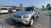 Silver Jeep SUV in a crowded car dealership lot with EZ Loan Auto Sales sign in background.