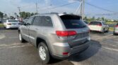 Silver Jeep SUV in a busy parking lot with other cars and overhead power lines in view.