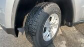 Close-up of a car tire mounted on a silver wheel, inside the wheel well of the vehicle, showing tread details.