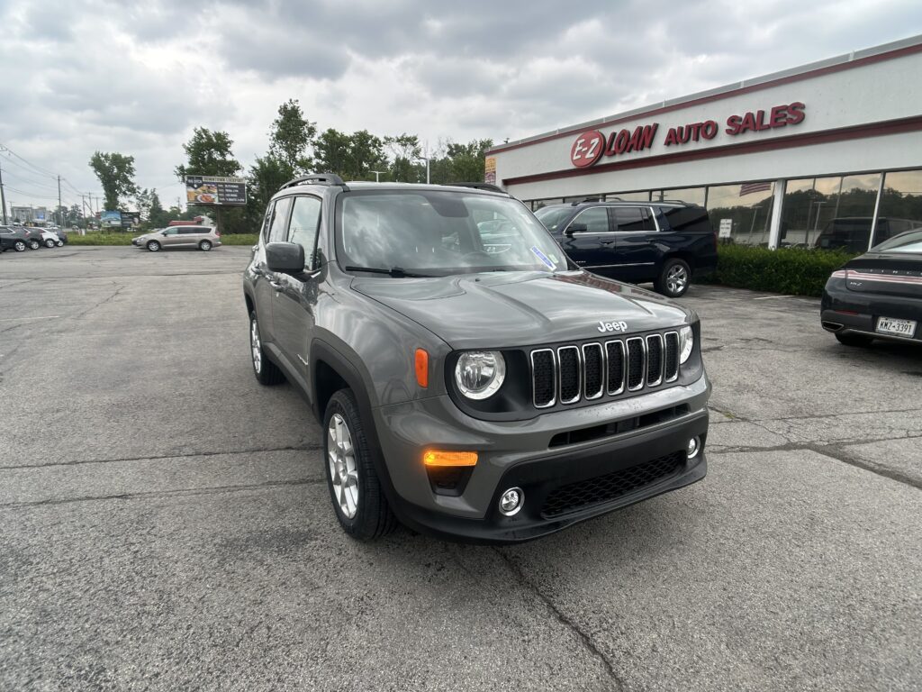 Grey Jeep SUV in foreground at a car dealership lot with EZ Loan Auto Sales sign in the background