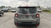 Rear view of a gray Jeep SUV in a parking lot, other cars around, under a cloudy sky