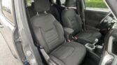 Interior of a car with black fabric seats, front row visible, driver door open, center console and gear shift in view.