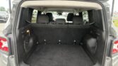 Open rear hatch of a gray SUV showing a large, empty cargo area with upright third-row seats and side storage pockets in the corners.