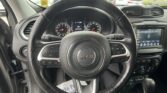 Inside a Jeep SUV cockpit: steering wheel with Jeep emblem, instrument cluster, and the tablet-style infotainment screen on the right side of the dash.
