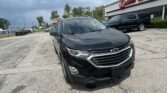 Close-up of a black Chevrolet SUV in a car lot, with an EZ Loan Auto Sales storefront in the background under a cloudy sky.