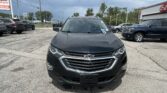 Front view of a black Chevrolet SUV parked in a lot, dealership lot with other cars and signage in the background