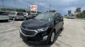 Black Chevrolet SUV in a crowded parking lot with a red EZ Auto Sales sign in the background under a cloudy sky