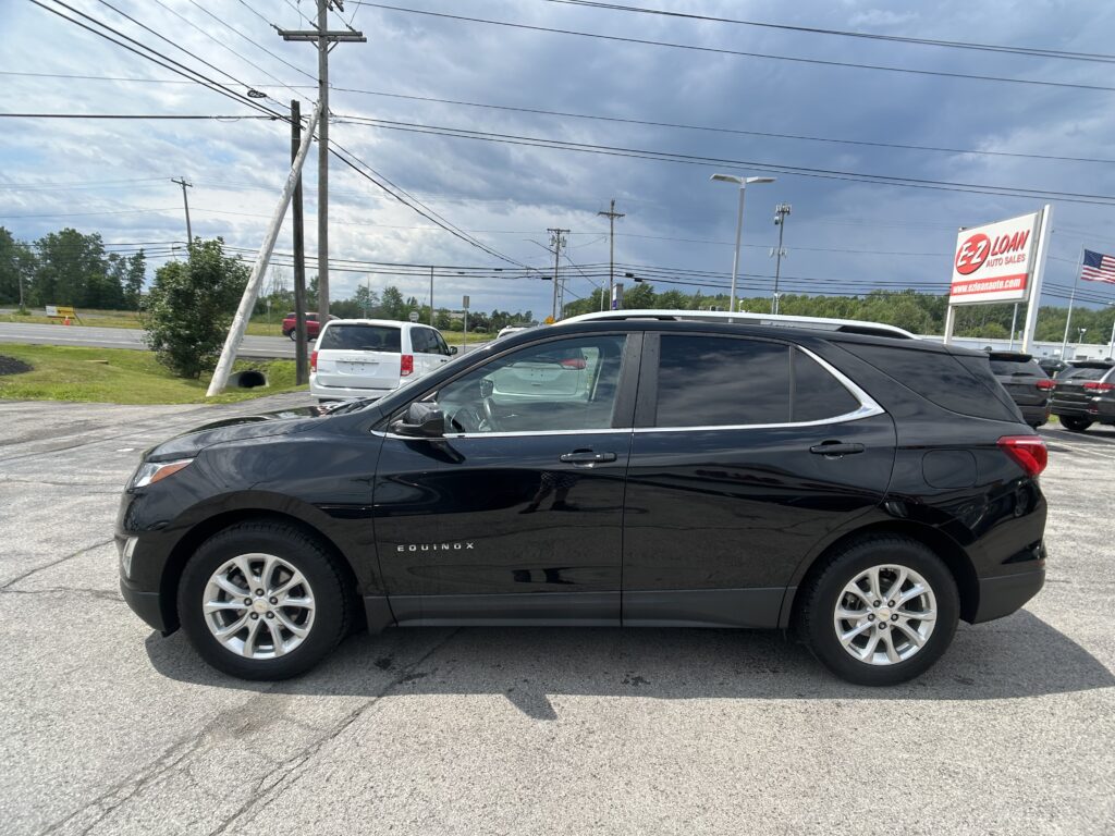 Black Chevrolet Equinox in a parking lot, with a large EZ-LOAN Auto Sales sign and a partly cloudy sky in the background.