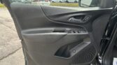 Interior of a car door panel featuring a chrome door handle and window controls on a black textured surface, with a parking lot visible outside the window.