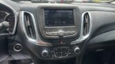 Interior of a car dashboard with a touchscreen radio showing 96.9 Rock and control buttons below; view of a parking lot through the windshield.