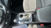Front passenger seat and center console of a car, with cup holders, gear shifter, and a paper lying on the floor mat