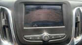 Rear-view camera display on car screen showing parking lot with orange guide lines to assist reversing.