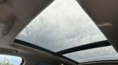 Sky view through a car sunroof with raindrops on the glass, showing a cloudy day outside.